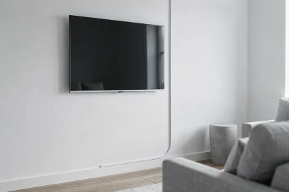 TV murale avec goulotte plastique blanche fixée verticalement sur mur blanc, rendu épuré façon showroom dans salon scandinave